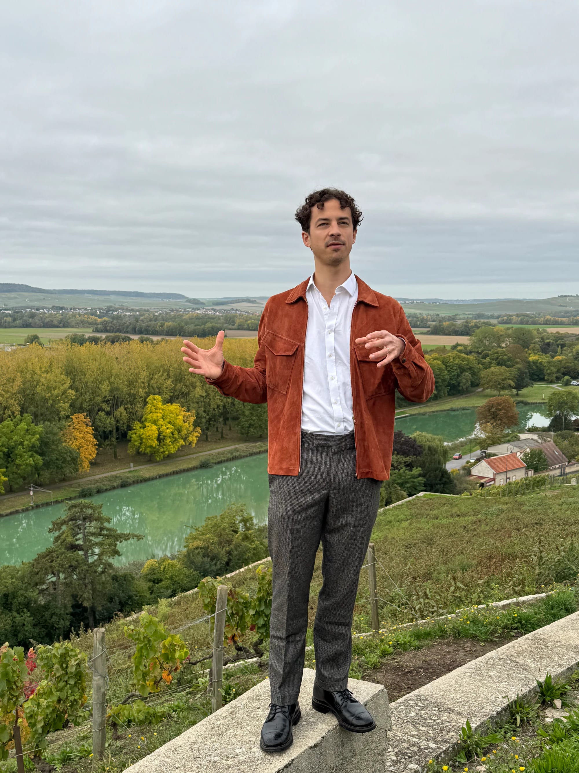 A man standing at a vineyard overlooking the valley